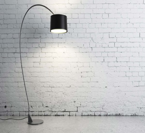 Zu sehen ist eine schwarze Stehlampe vor einer weißen Bruchsteinmauer.