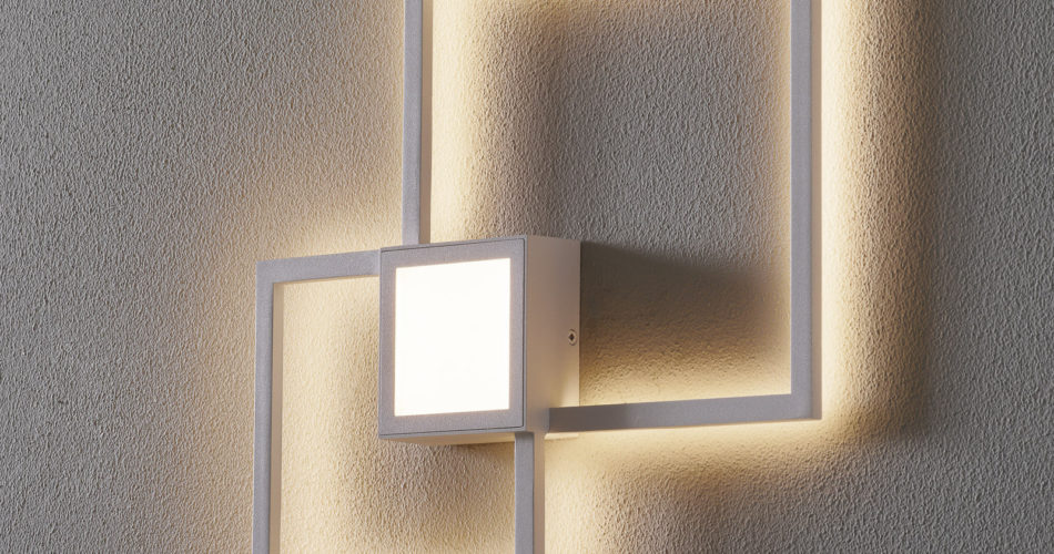 Zu sehen ist eine weiße Wandleuchte mit einem Quadrat in der Mitte wo sich die Leuchte befindet und 2 l-förmige Formen die sich oben recht und unten links befinden.